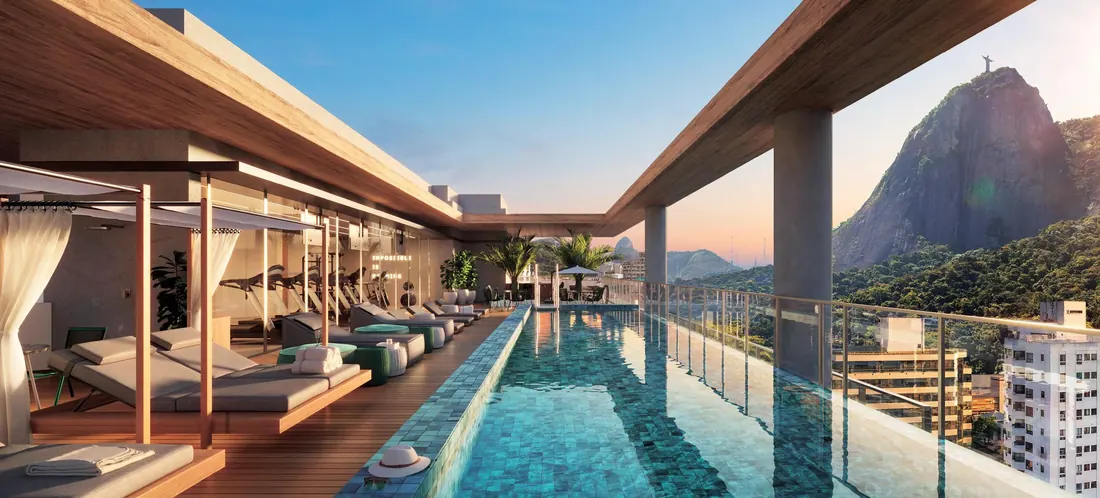 Piscina com pool bar e espreguiçadeiras no rooftop do First Humaitá, com vista para o Corcovado